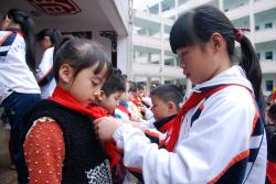 老队员为新队员带上红领巾